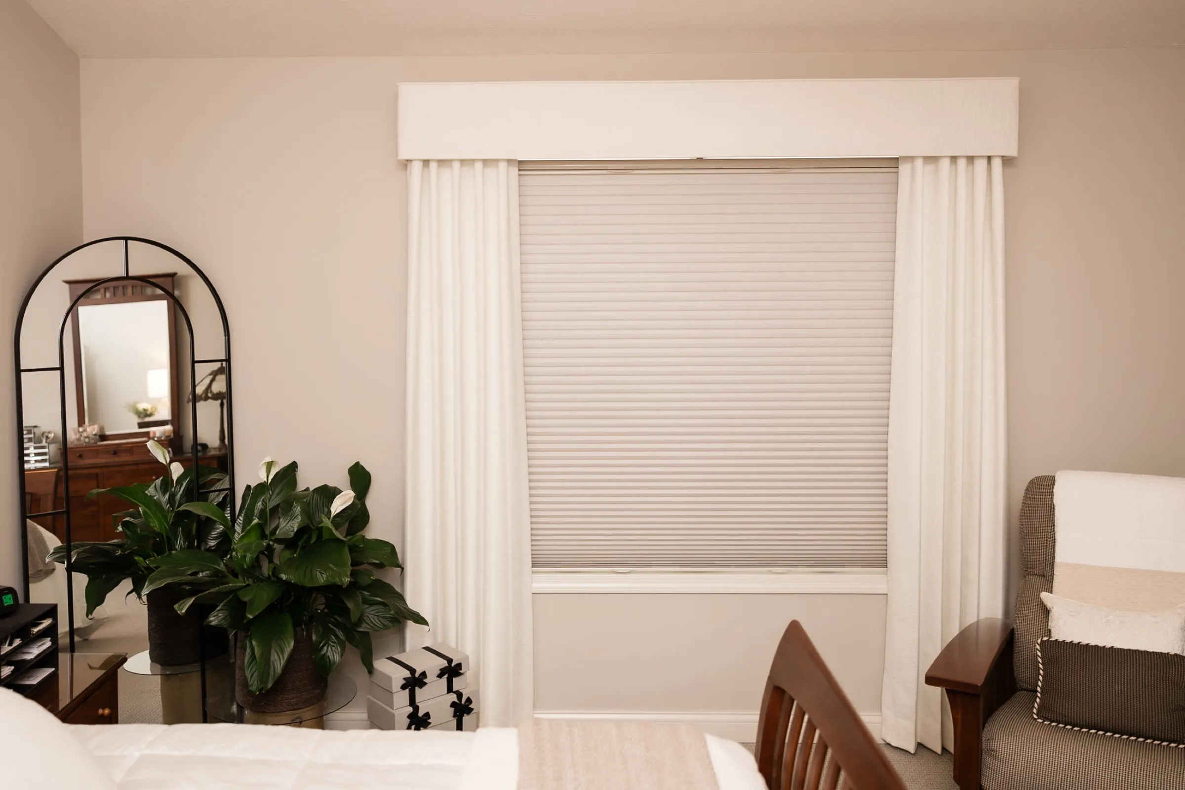 Bedroom window with a cellular shade under a fabric valance and drapery panels