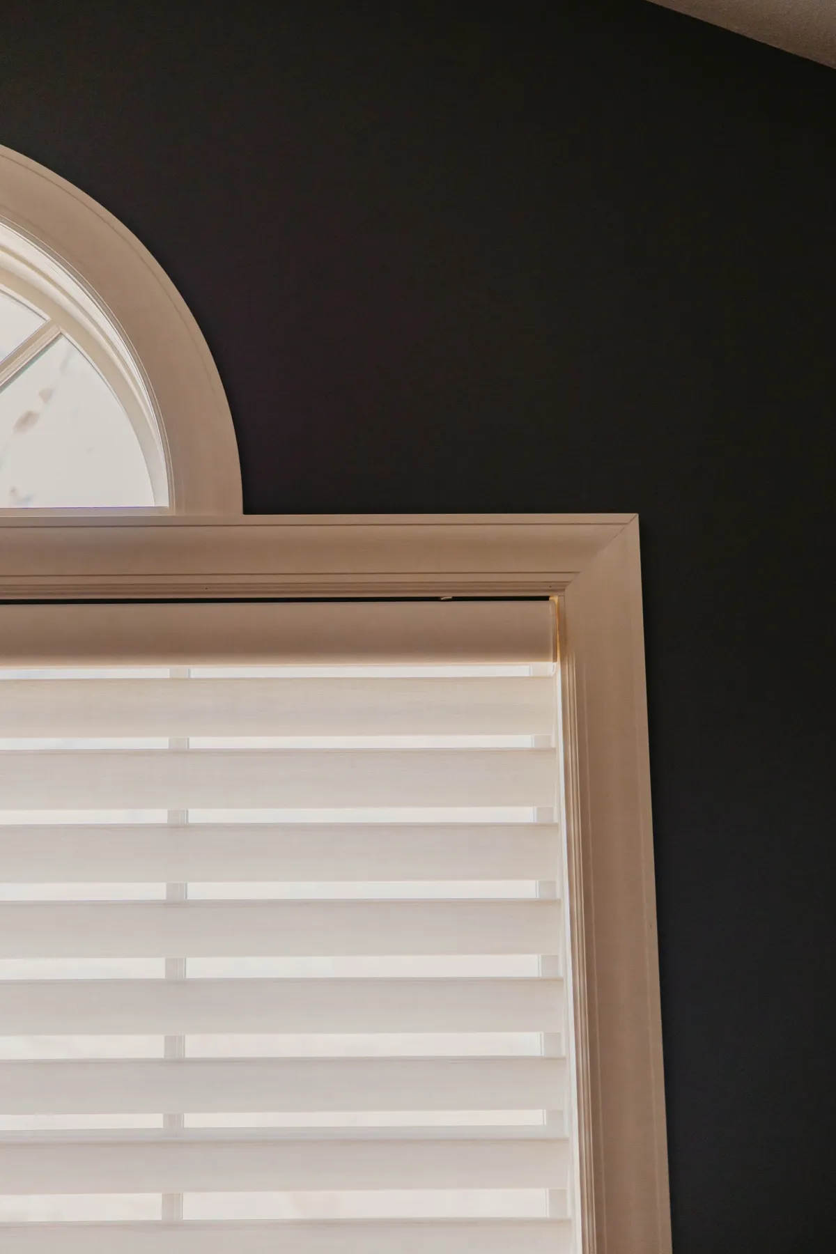 Pirouette® shade fitted under an arched window in a dark den