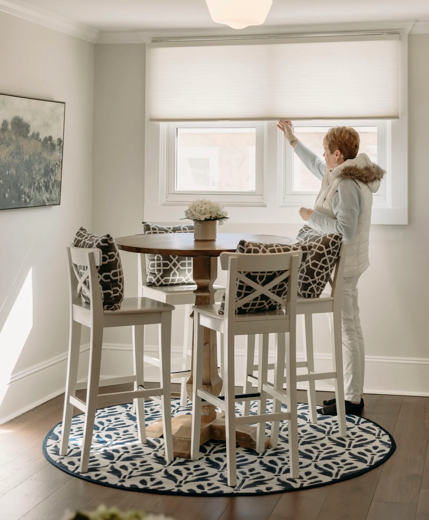 Breakfast nook window with a cellular shade being lowered