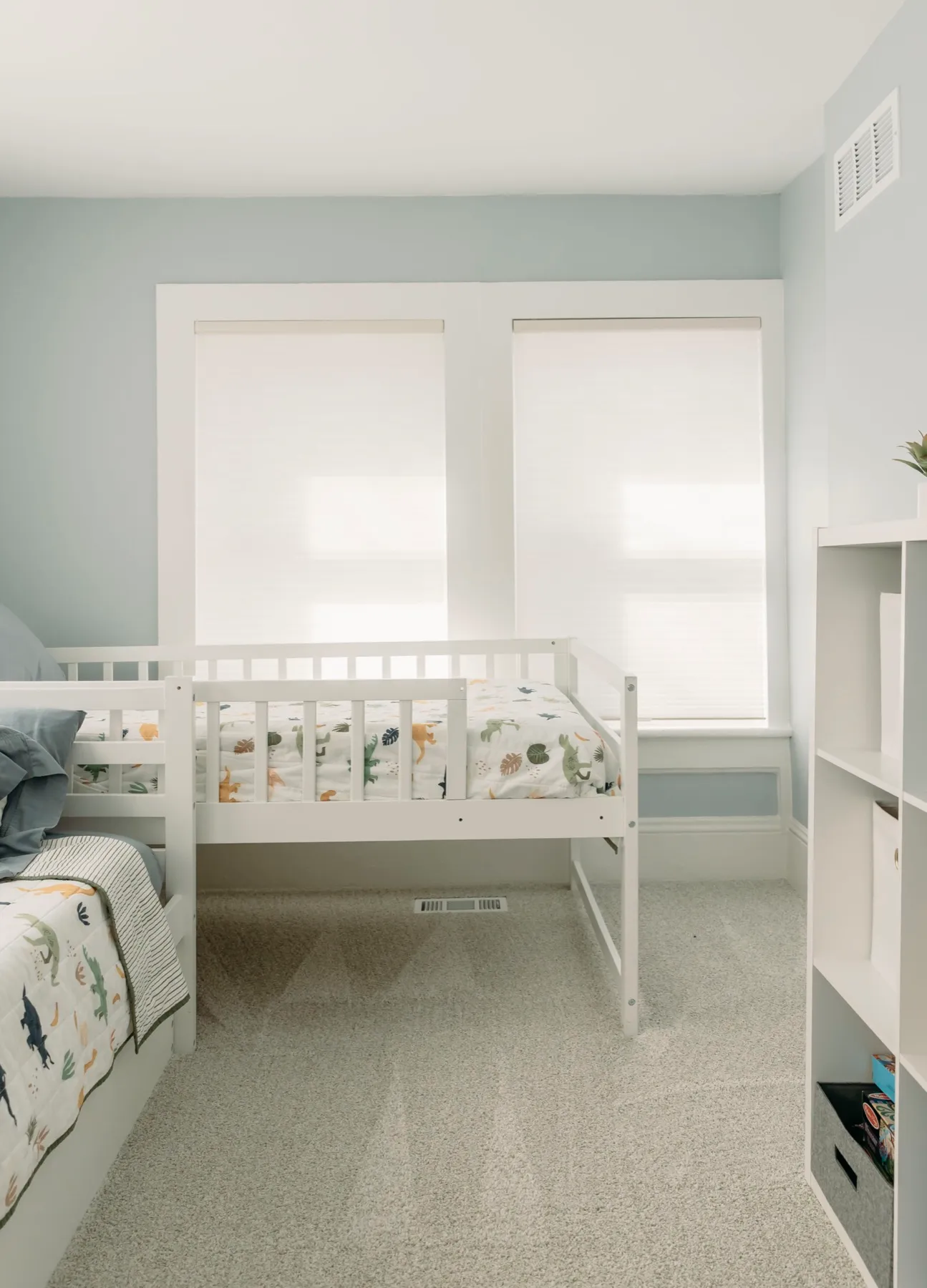 Kids' room with shades lowered behind a white bed