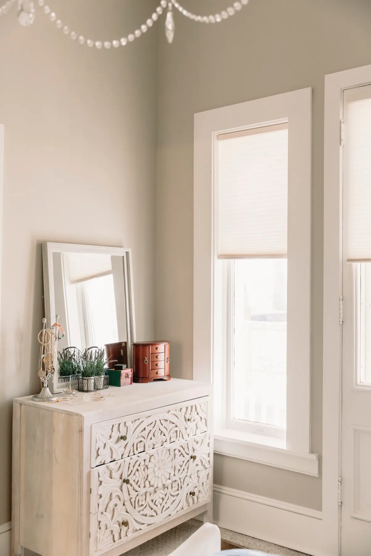 Bedroom corner with cellular shades above a carved dresser