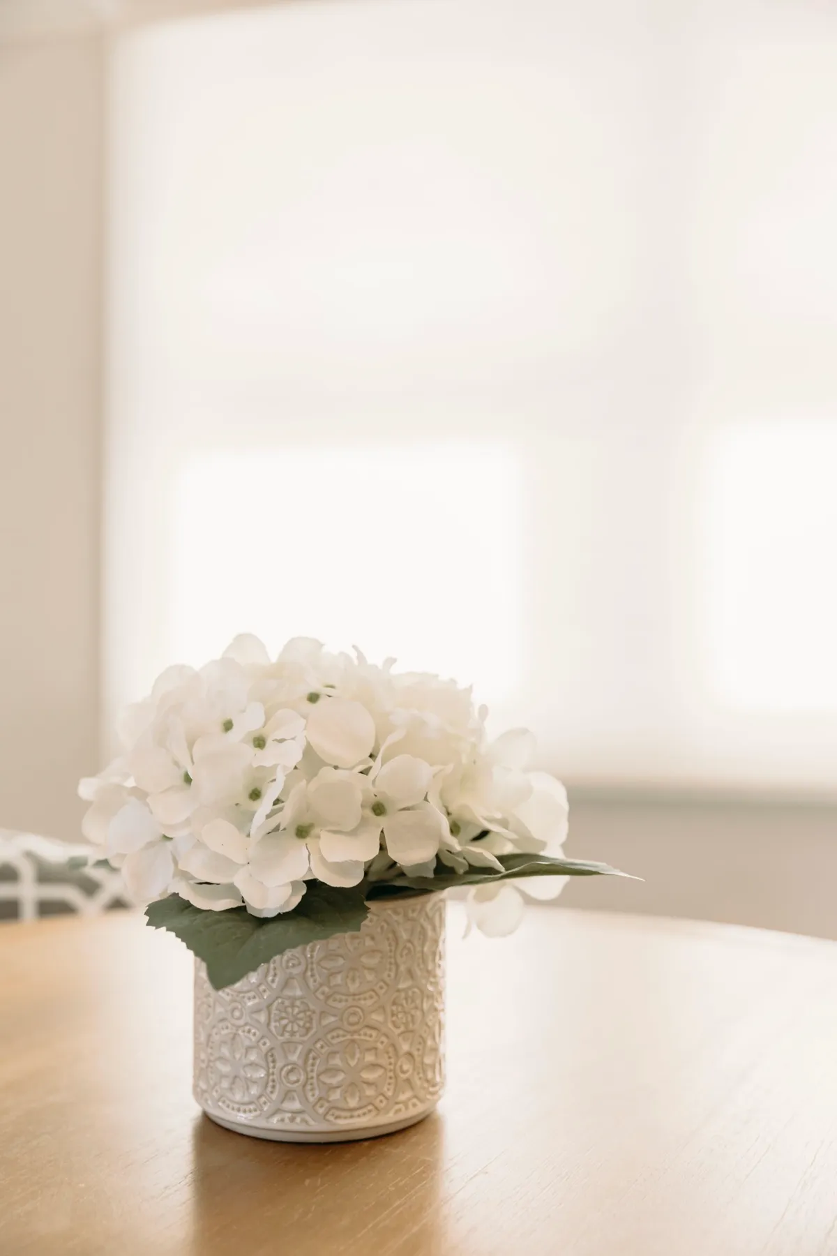 Soft light through a lowered shade behind a vase of flowers