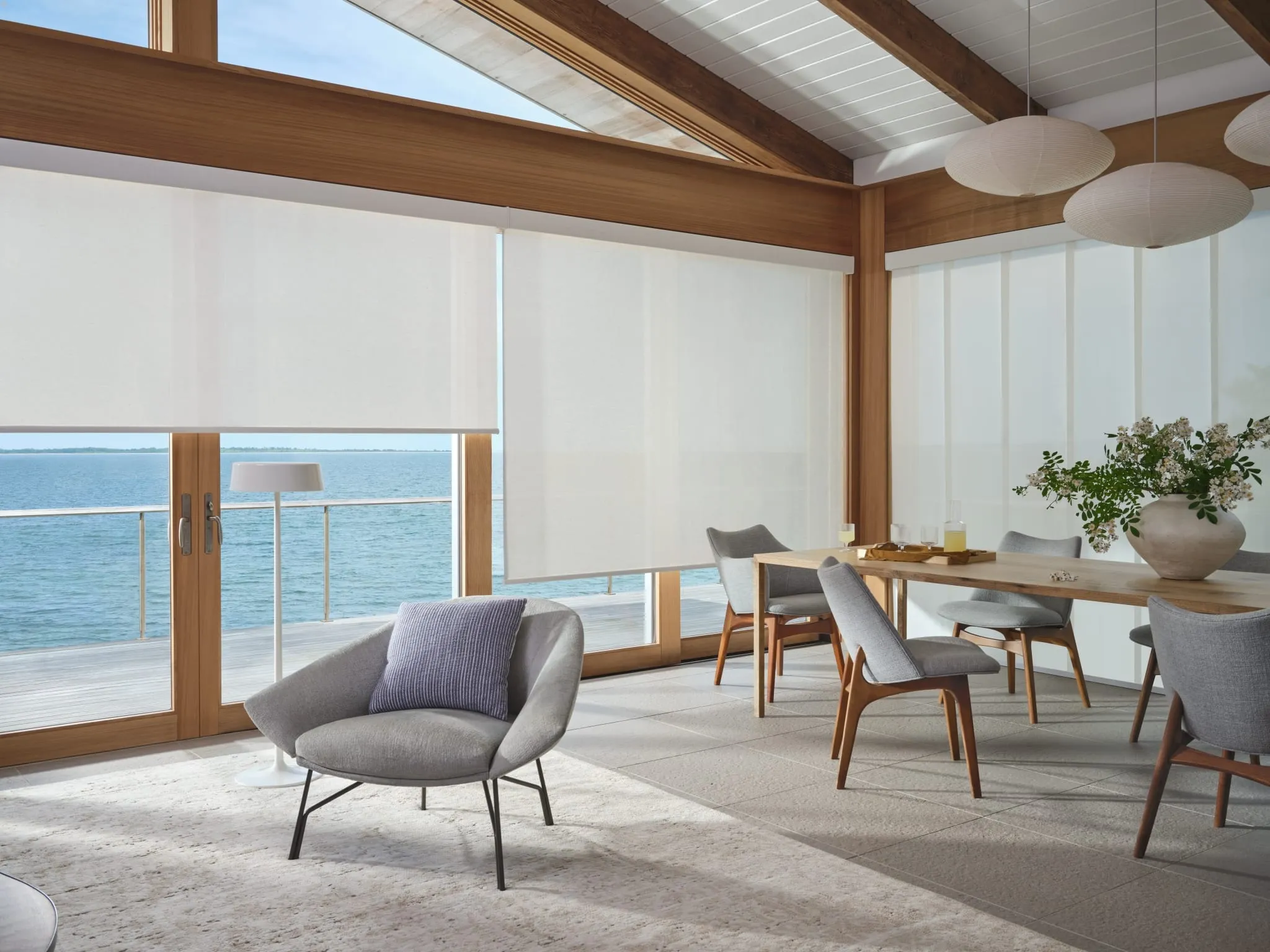Designer screen shades on ocean-view windows in a dining room, with Skyline® panels beyond