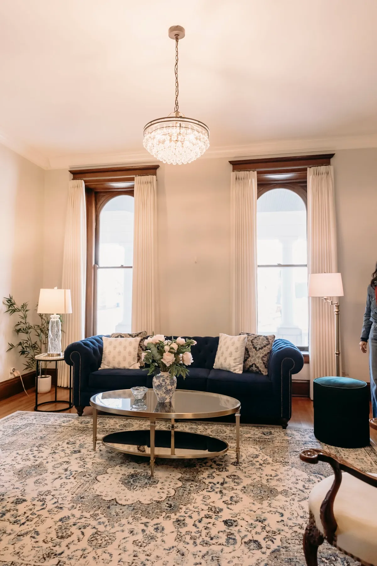 Living room with draperies on both arched windows under a chandelier