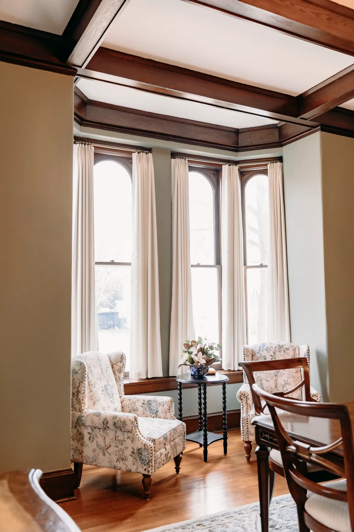 Bay window seating area framed by ivory draperies