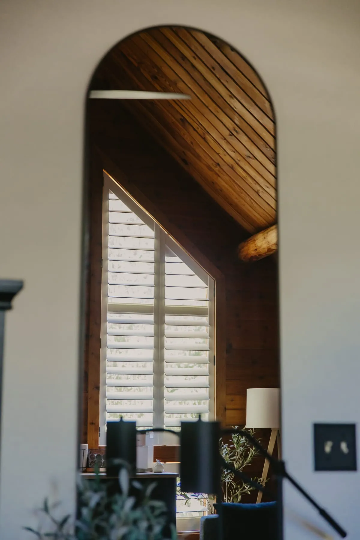 Arched window with white shutters in a wood-paneled room