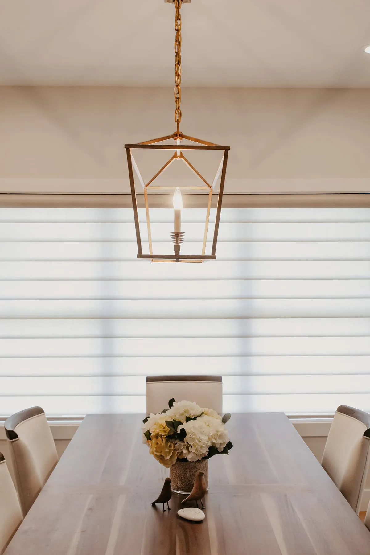 Dining room with sheer shades under a lantern light