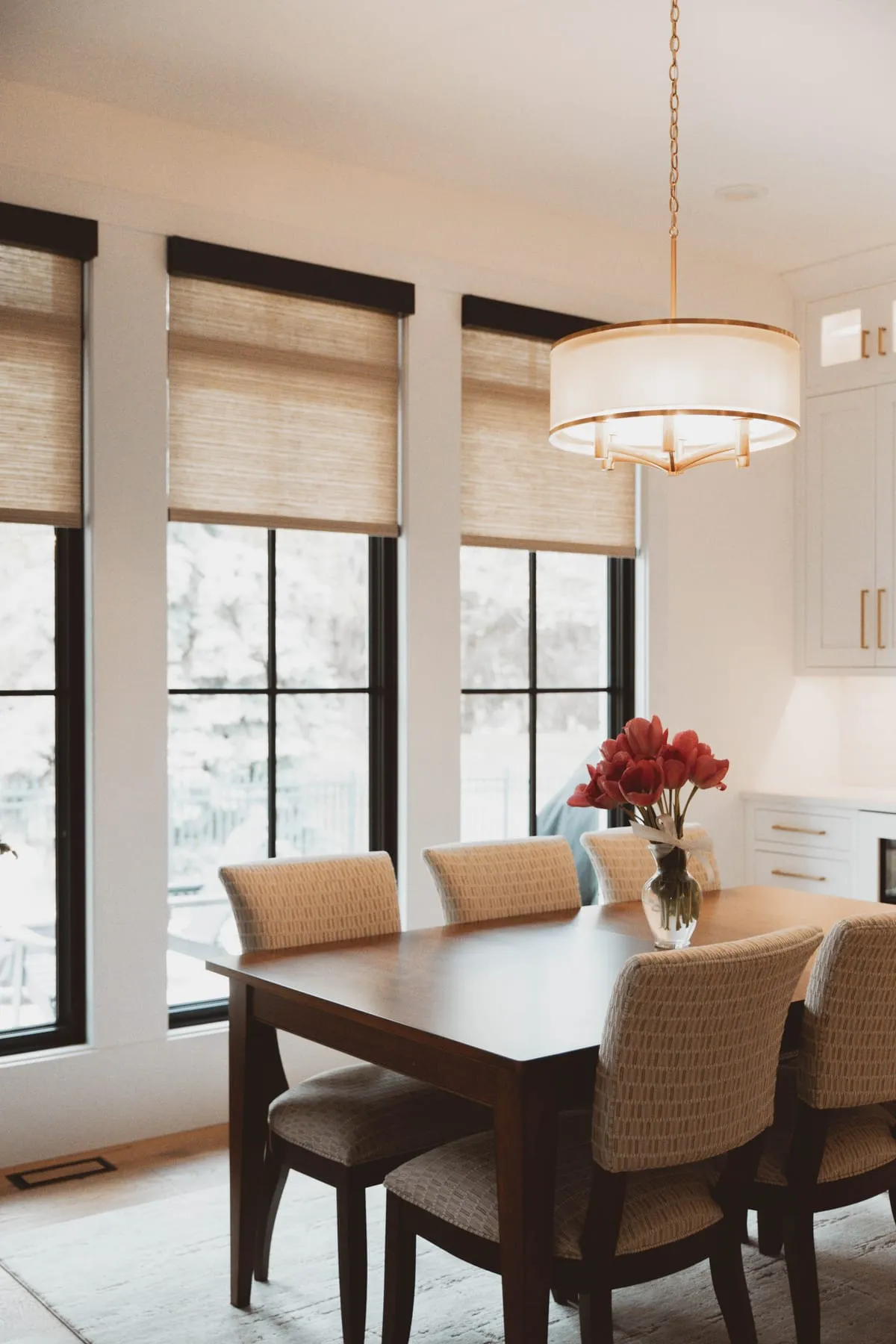 Dining room with woven shades on three tall windows