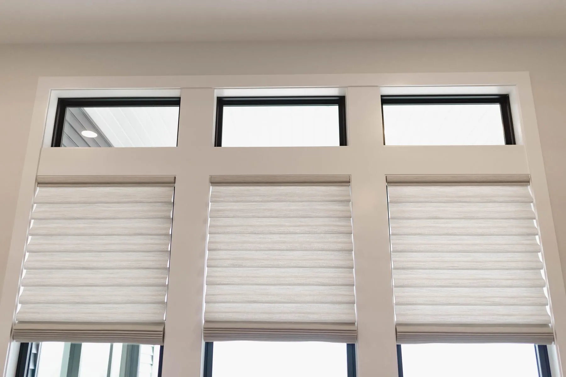 Three soft fabric shades below transom windows
