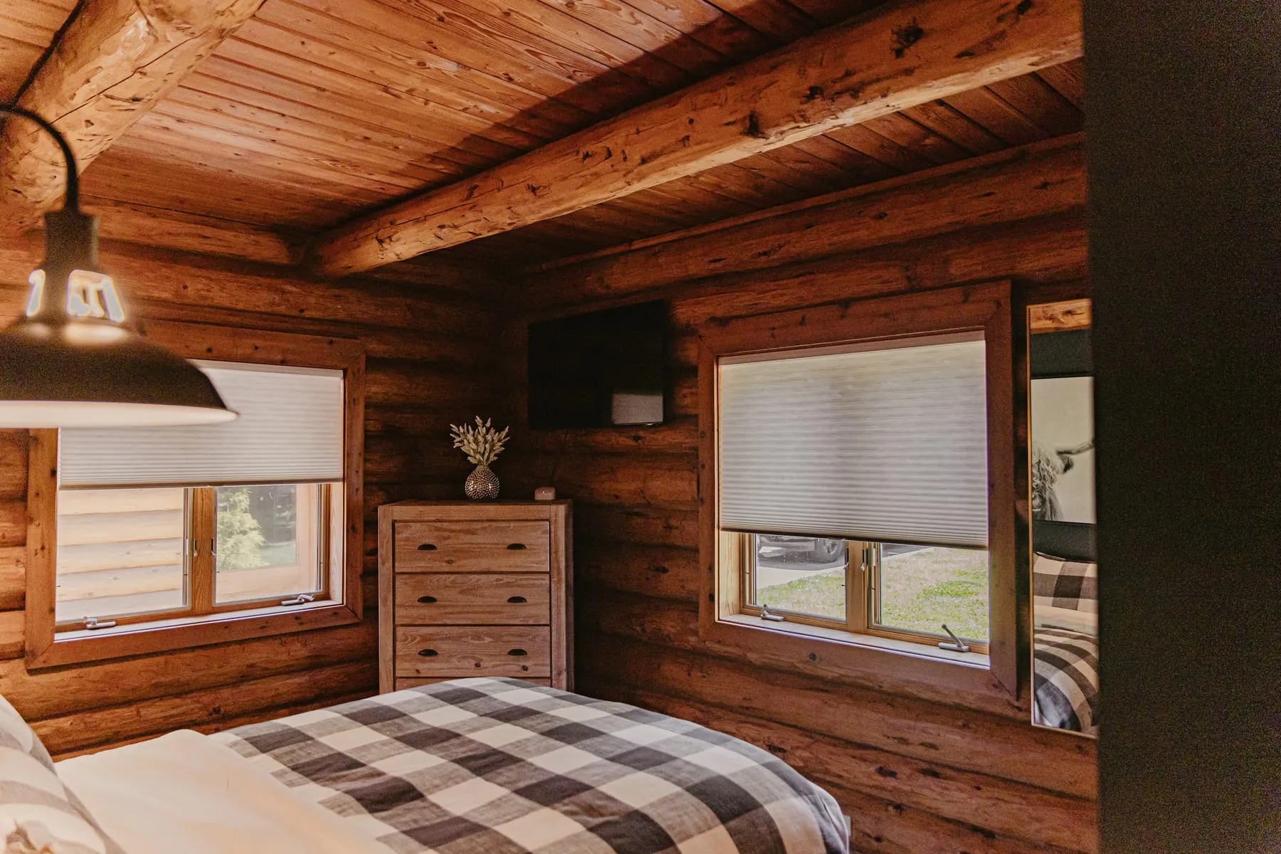Log cabin guest room with shades on both windows