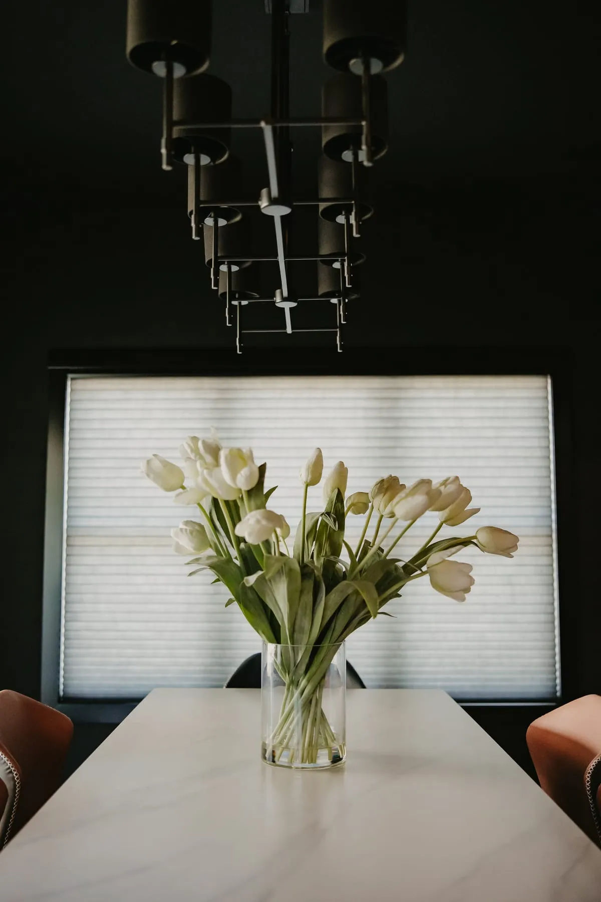 Dining table with tulips in front of a shaded window