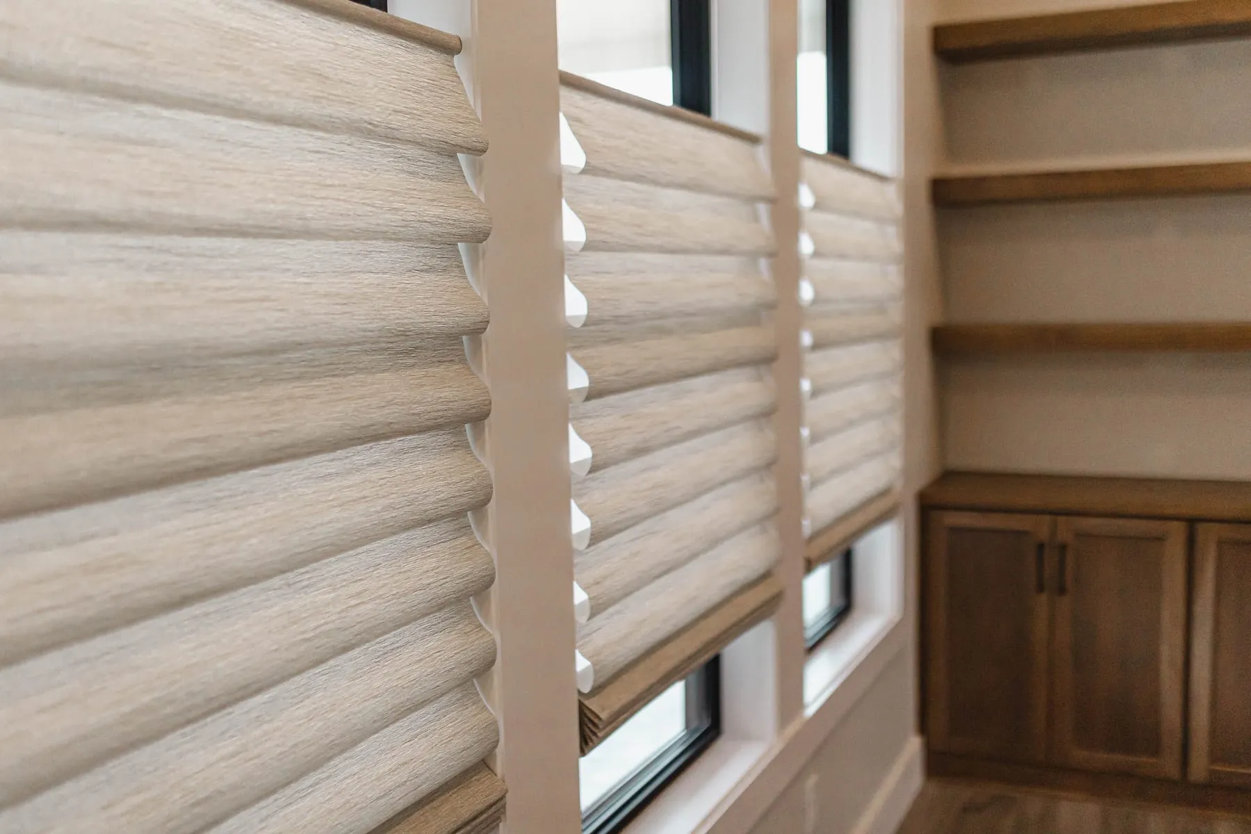 Row of soft fabric shades beside built-in cabinets