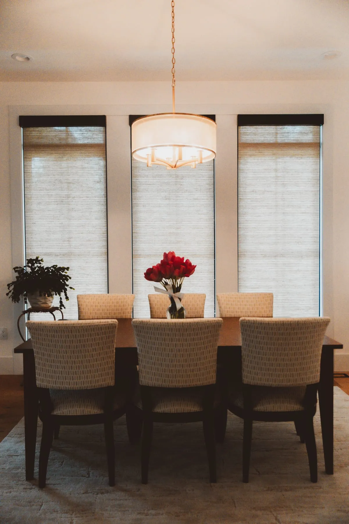 Dining room with woven shades and red flowers on the table