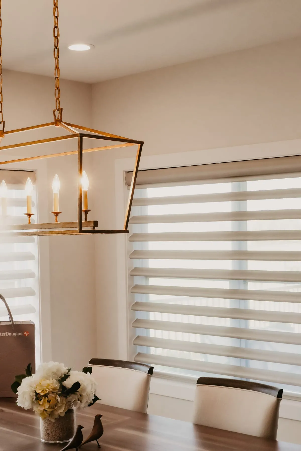 Sheer shades on a dining room window with a gold lantern