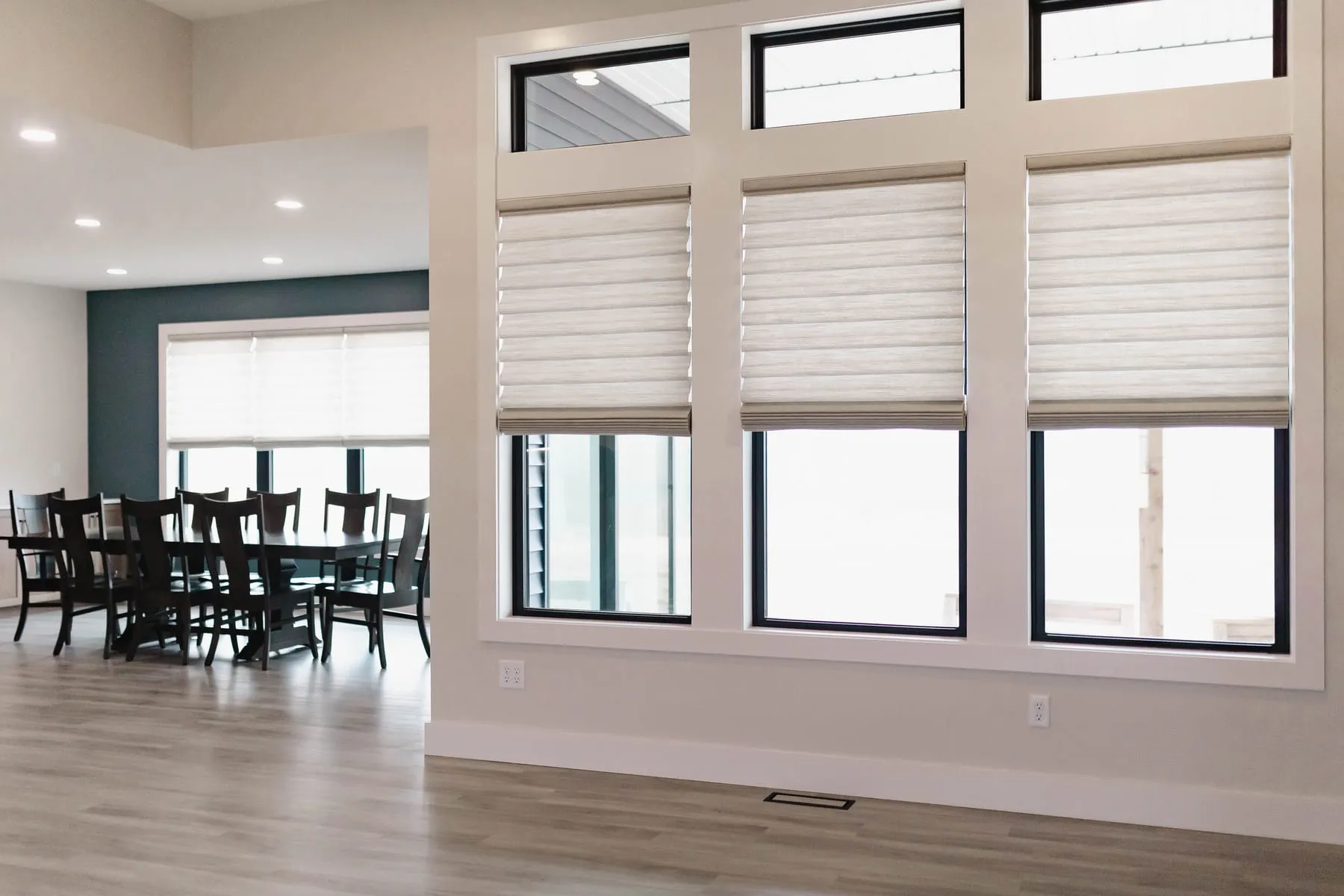 Open dining area with soft fabric shades on tall windows