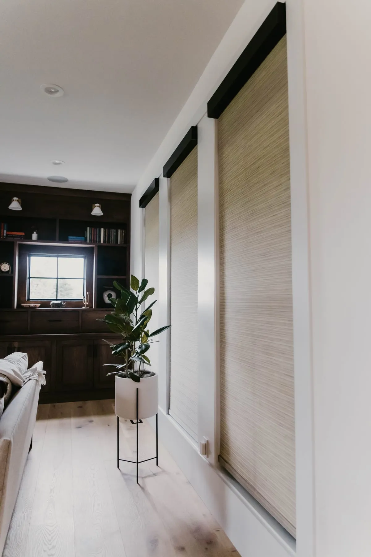Woven shades on tall windows with black trim