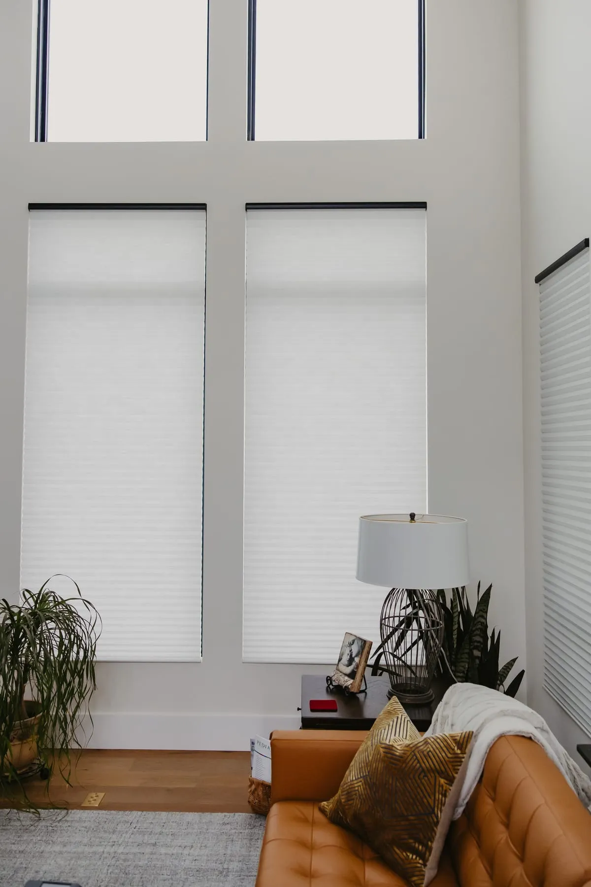 Shades on tall windows above a leather sofa