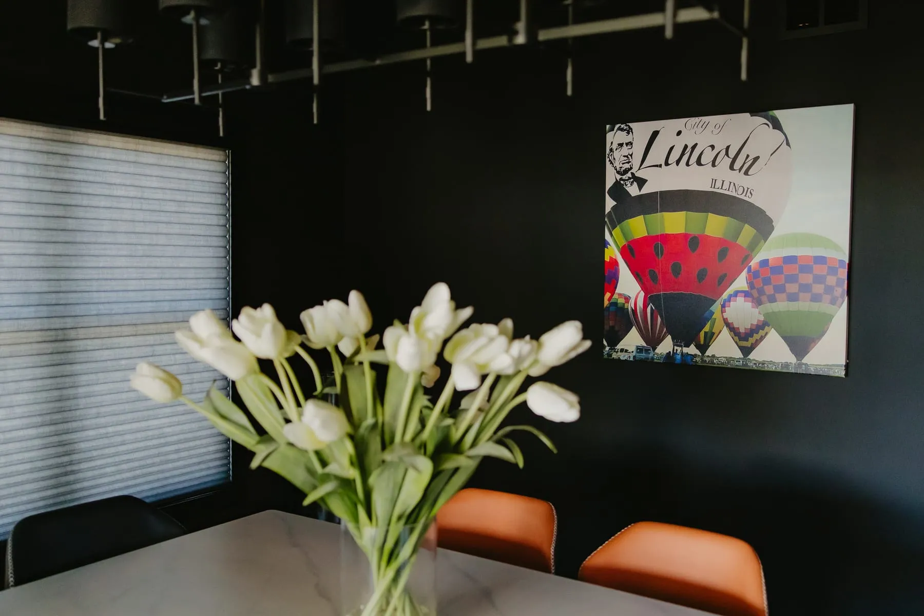 Dark dining room with shades, white tulips and a hot-air balloon print