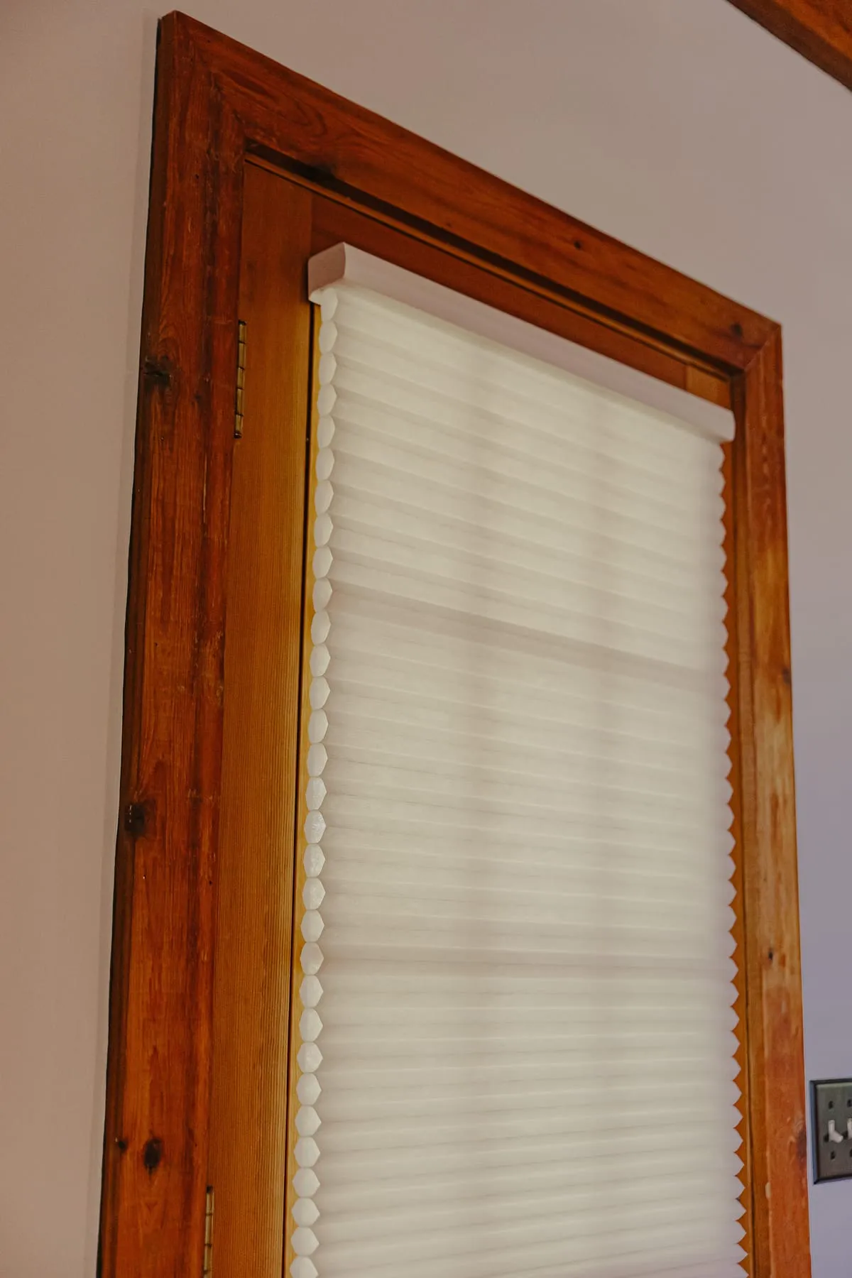 Light-filtering shade in a wood-trimmed window