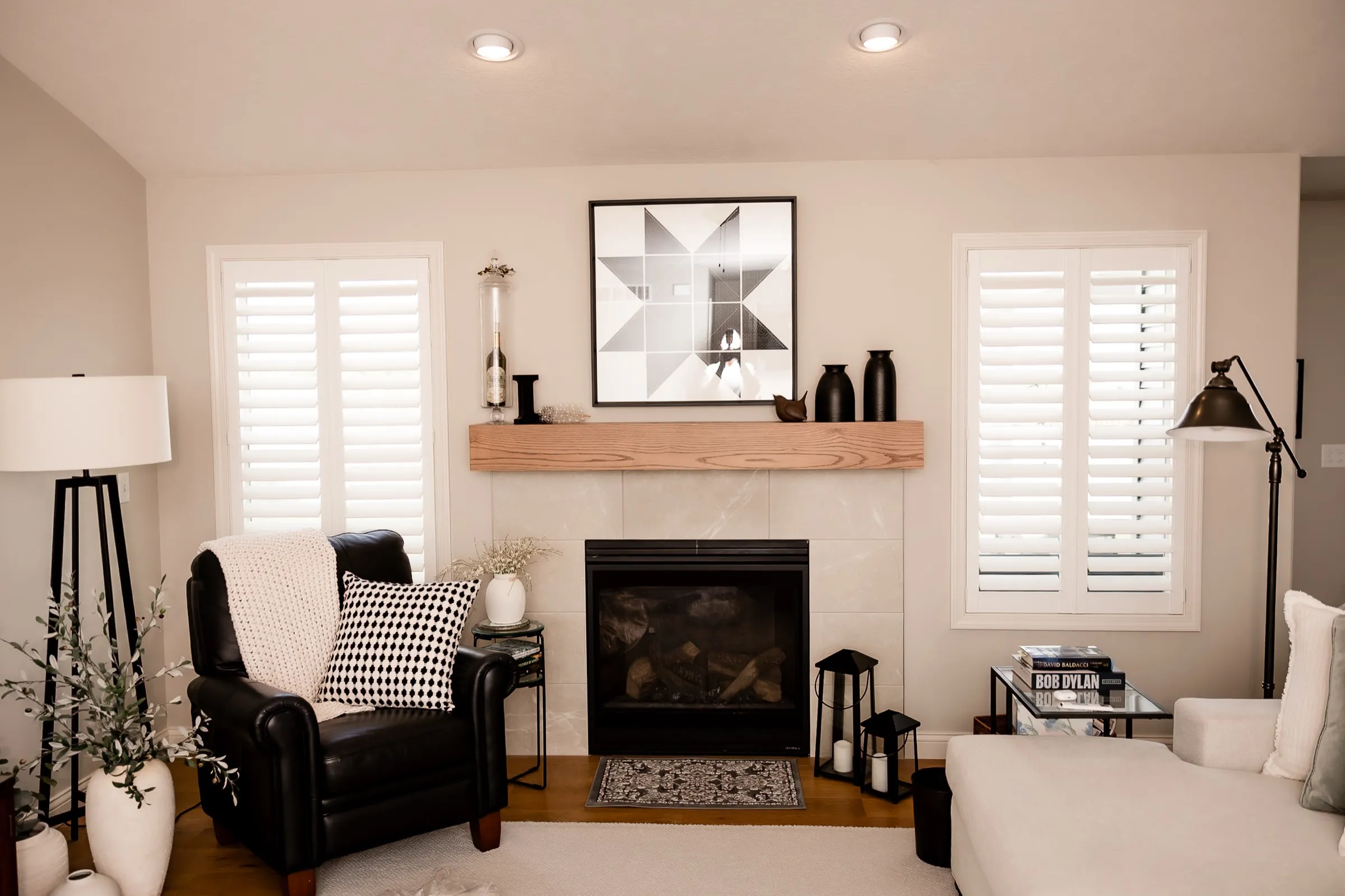 Living room with white shutters on the windows beside the fireplace