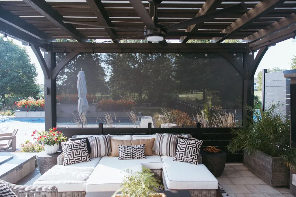 Backyard pergola with MagnaTrack motorized screens half lowered over an outdoor sectional