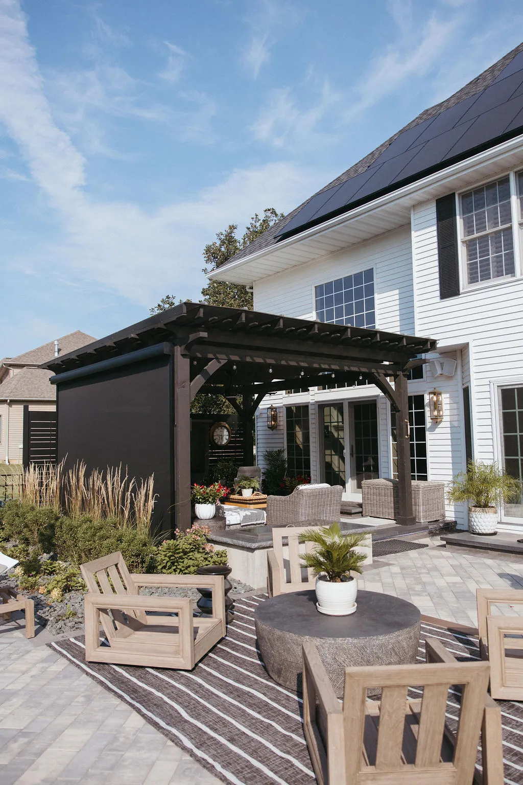 Pergola with screens down behind patio seating