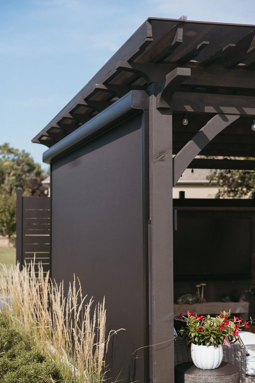 MagnaTrack screen lowered on the side of a dark pergola
