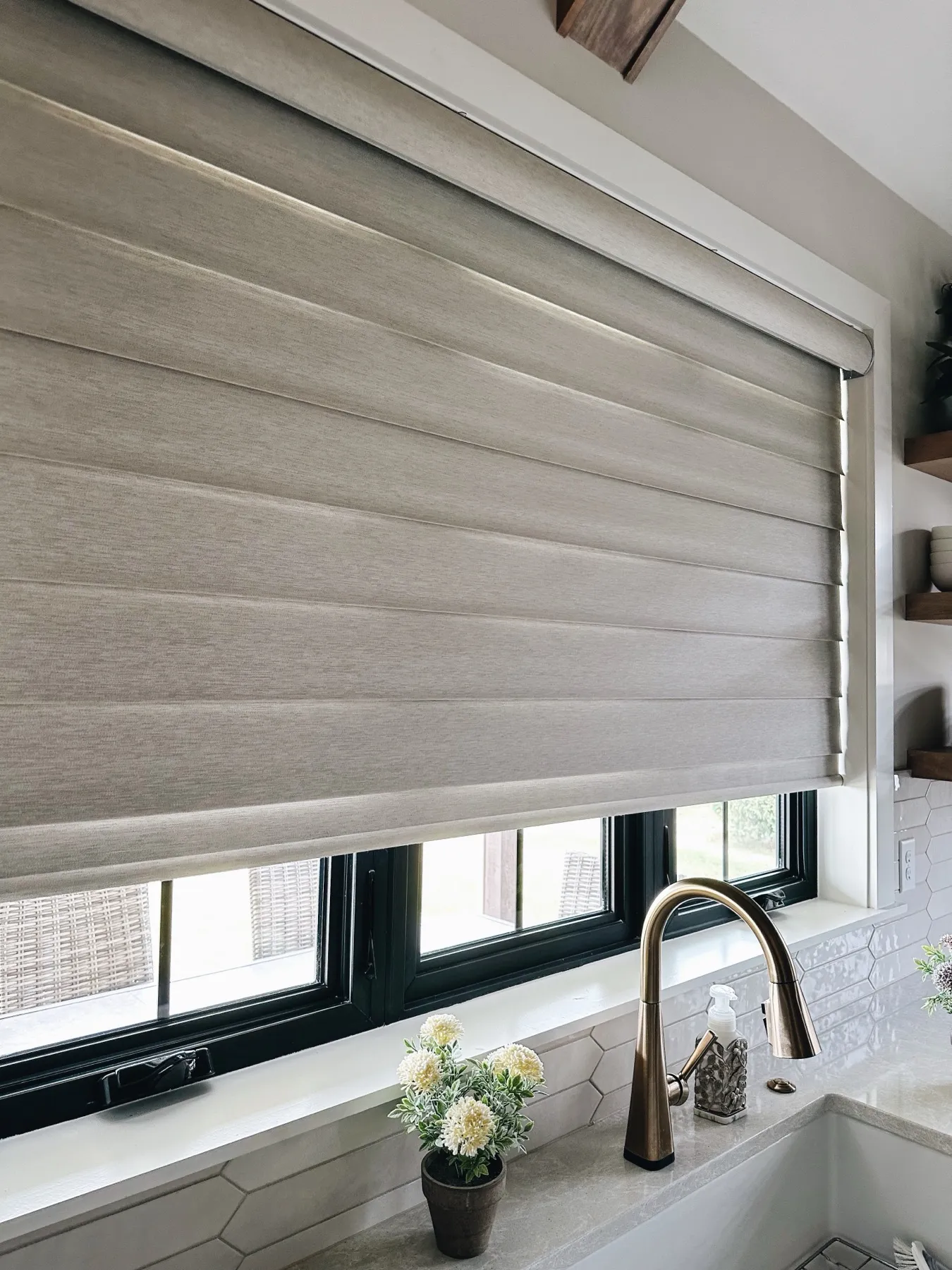 Pirouette® shade over a kitchen sink with black window frames