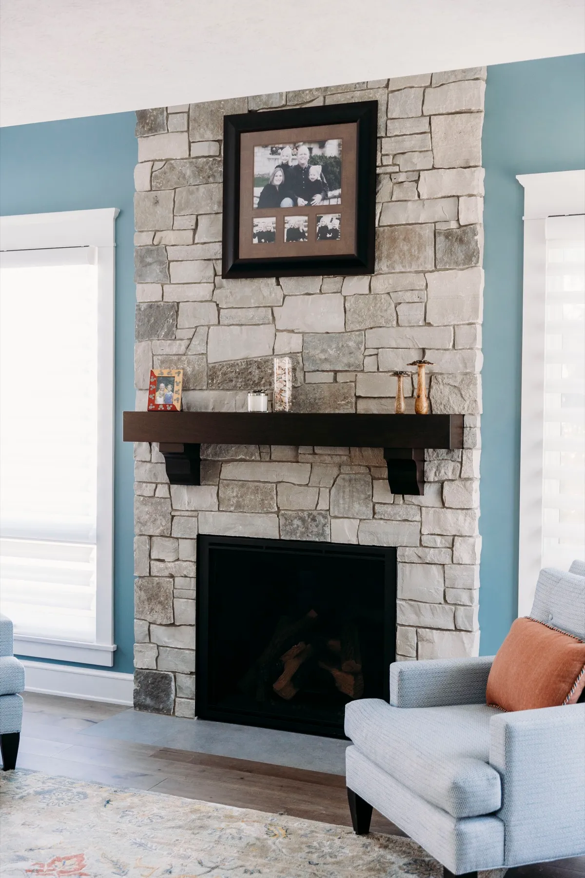 Stone fireplace flanked by windows with sheer shadings