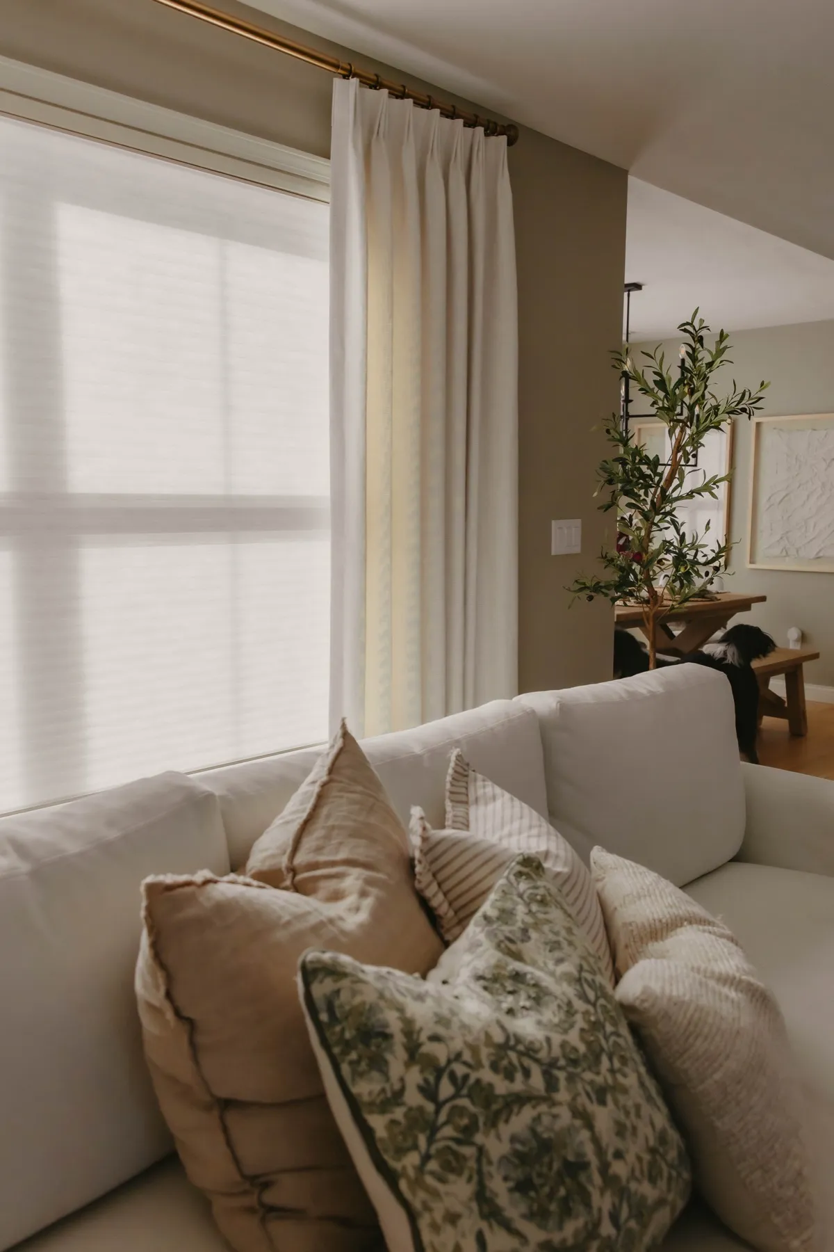 Ivory drapery panel on a brass rod beside a sectional