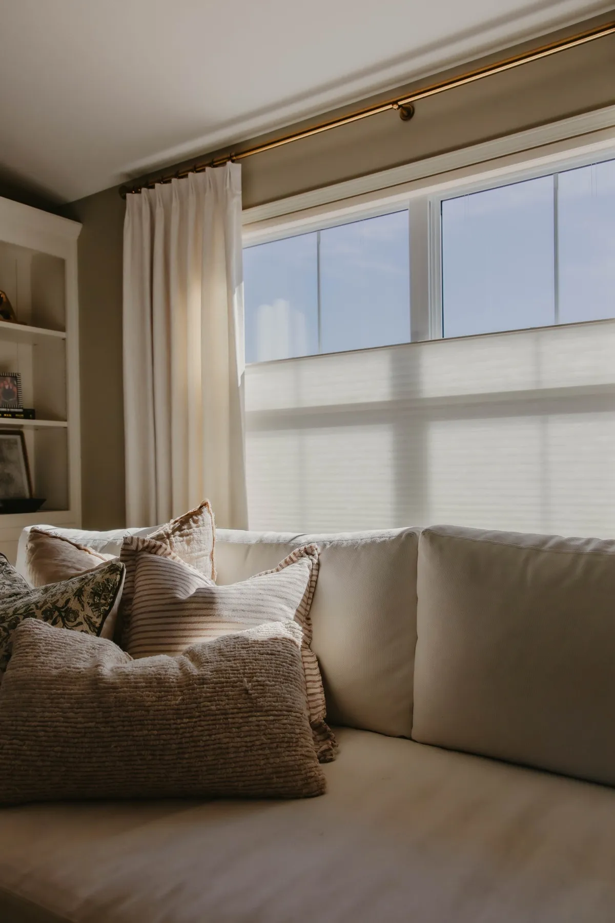 Sunlit window with drapery panels and shades lowered halfway