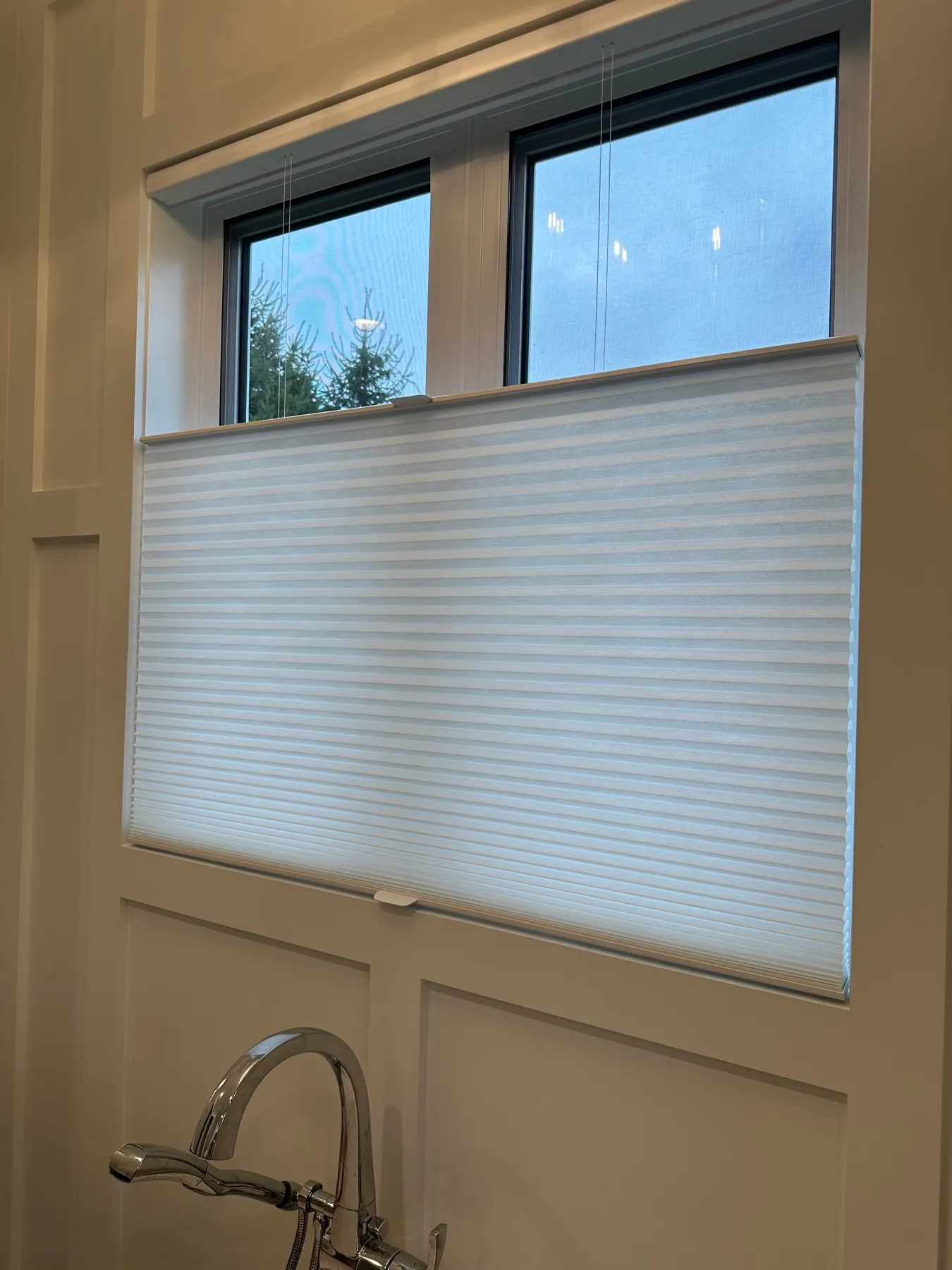 Kitchen window with a cellular shade lowered from the top