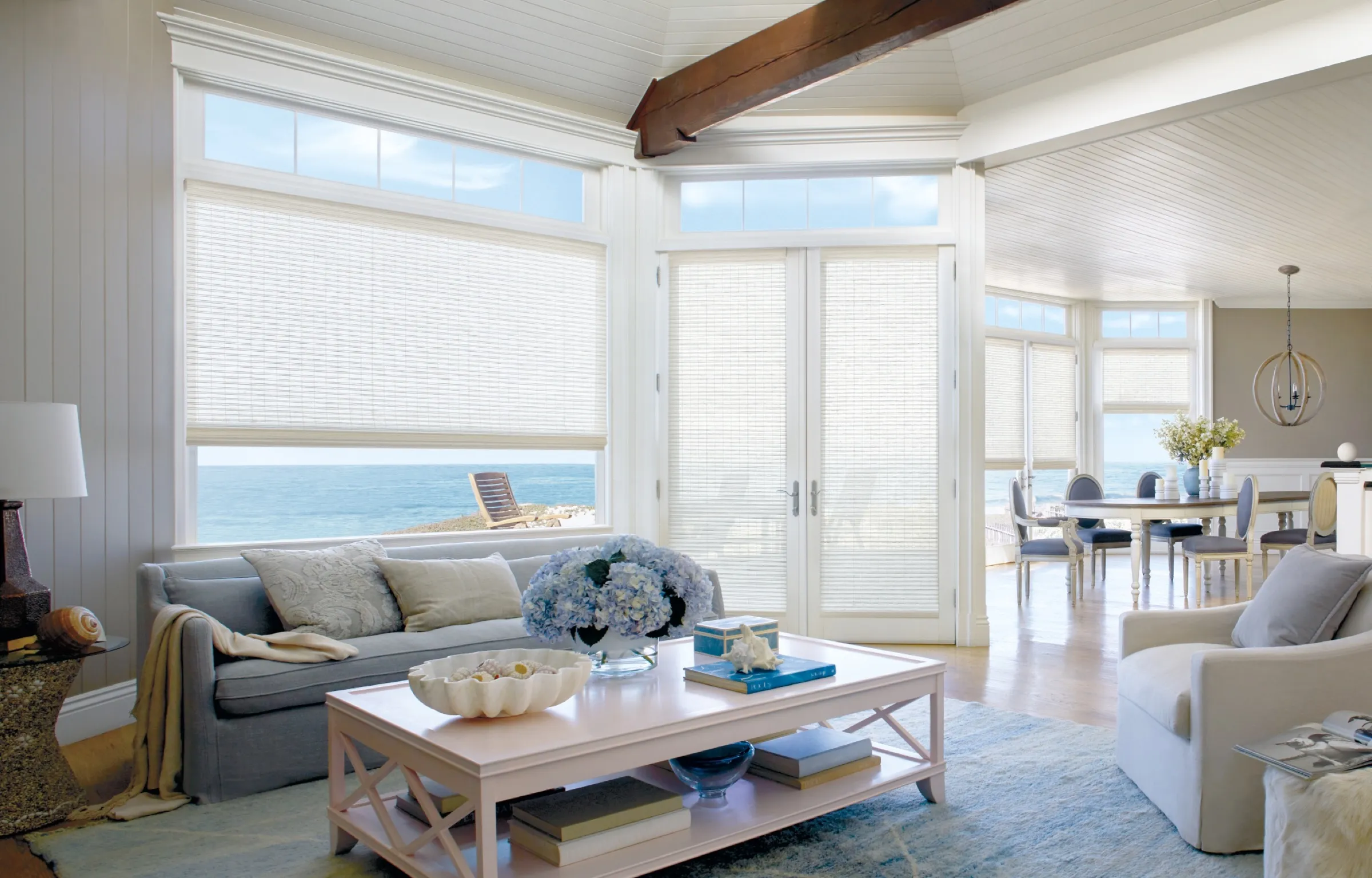 Provenance® Woven Wood Shades across the windows of a bright coastal living room
